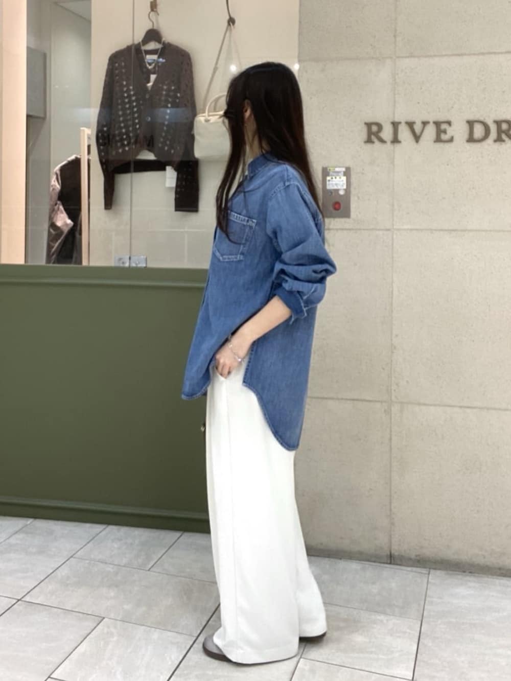 ホワイト系のスラックス、ブルー系のシャツ/ブラウス、ブラウン系のボストンバッグを着用したレディースの春コーディネートの2枚目の写真