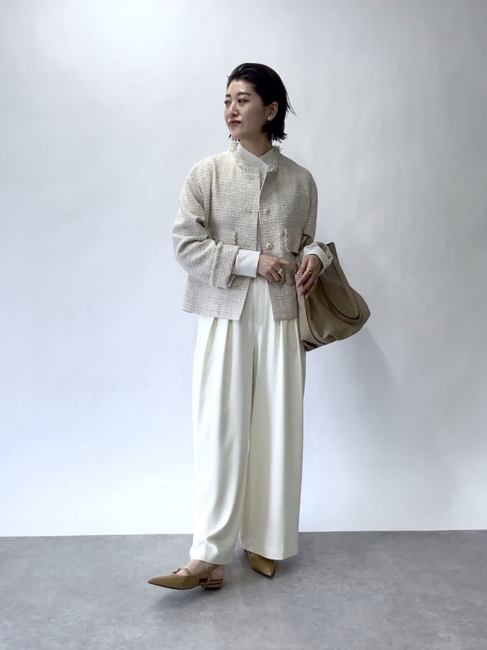 ホワイト系のスラックス、ベージュ系のノーカラージャケット、ベージュ系のトートバッグを着用したレディースの冬コーディネートの2枚目の写真