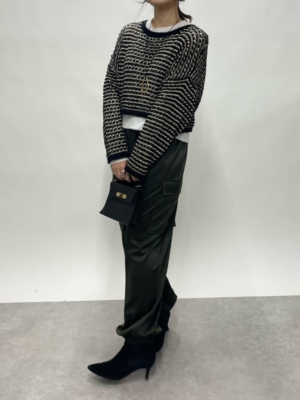 グリーン系のカーゴパンツ、ブラック系のハンドバッグ、ブラック系のブーツを着用したレディースの冬コーディネートの2枚目の写真