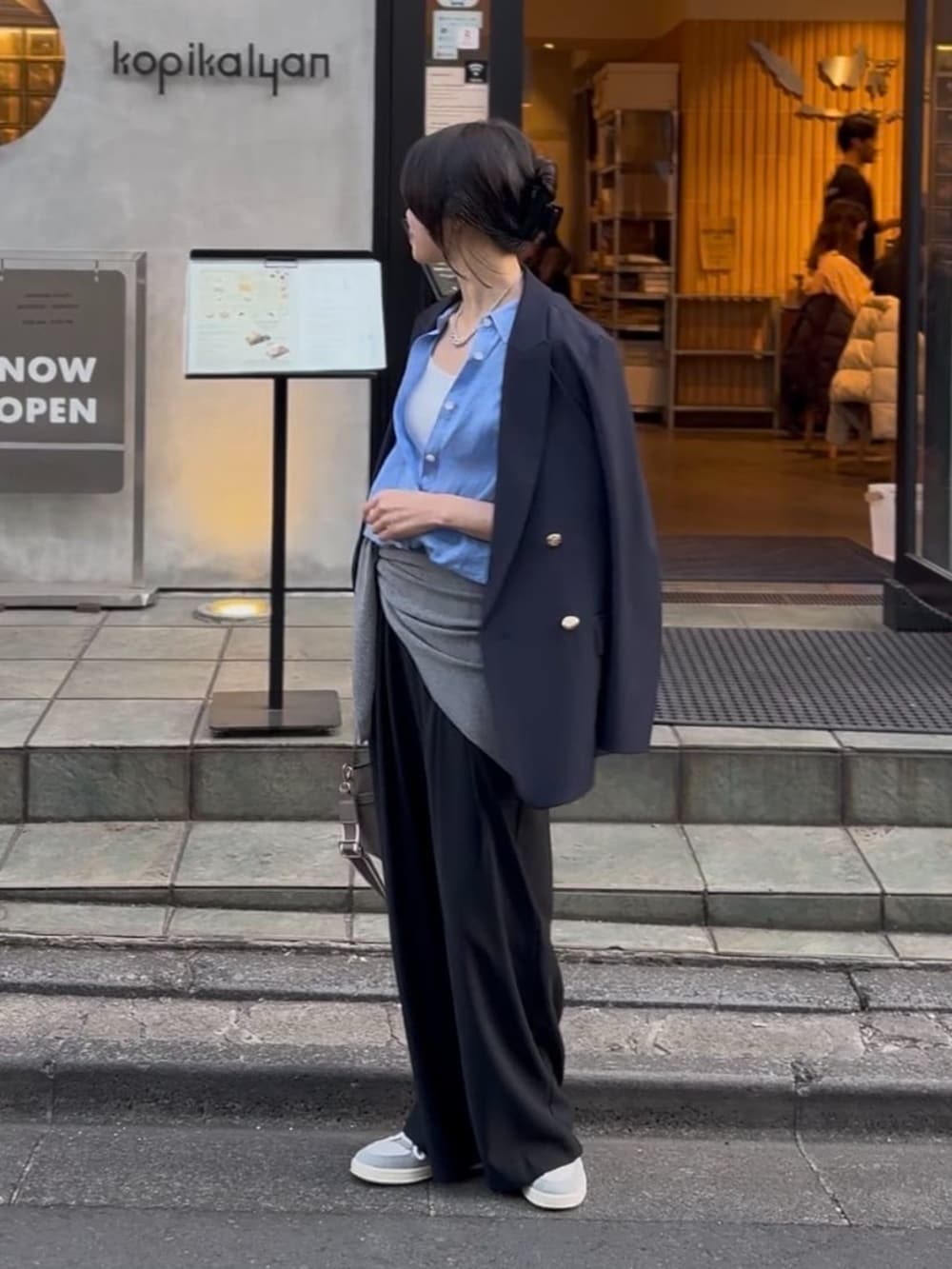 ブラック系のスラックス、グレー系のトートバッグ、ブルー系のテーラードジャケットを着用したレディースの冬コーディネートの3枚目の写真