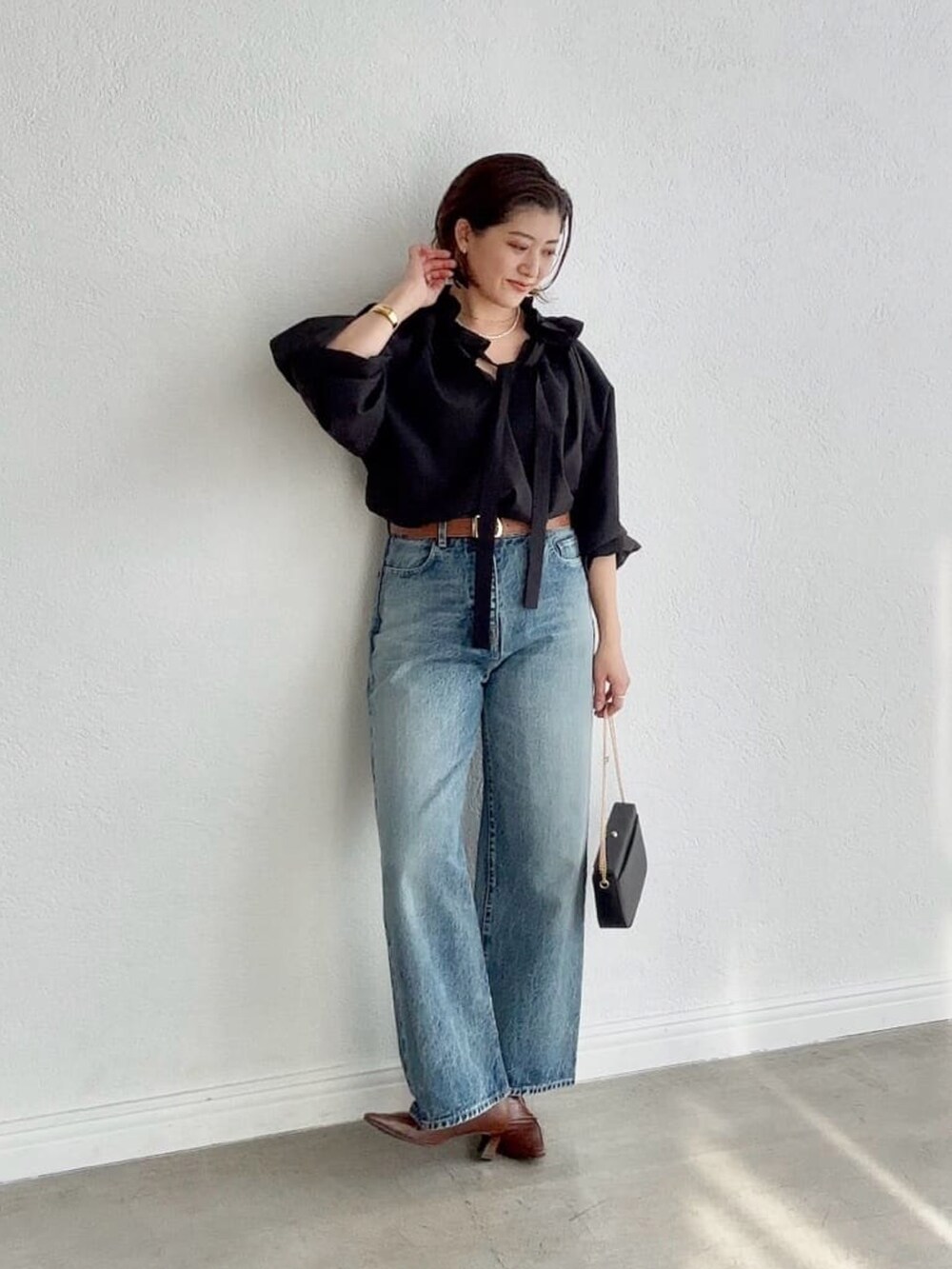 ブラック系のシャツ/ブラウス、ブルー系のデニムパンツ、ブラウン系のローファーを着用したレディースの冬コーディネートの2枚目の写真