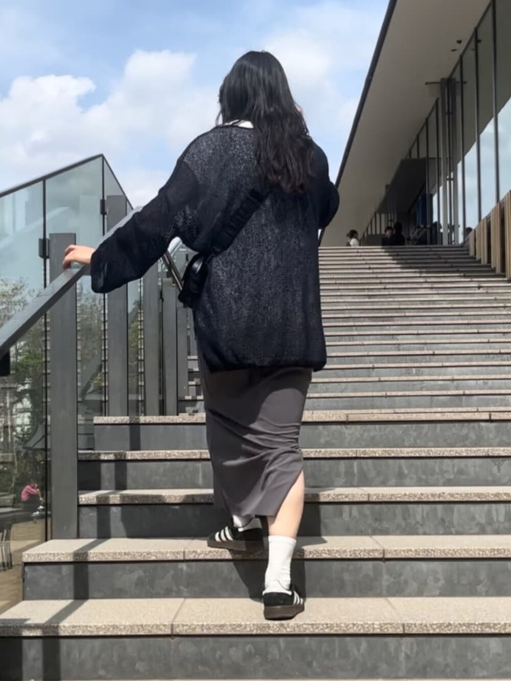 ブルー系のニット/セーター、ホワイト系のシャツ/ブラウス、ブラック系のスカートを着用したレディースの春コーディネートの3枚目の写真