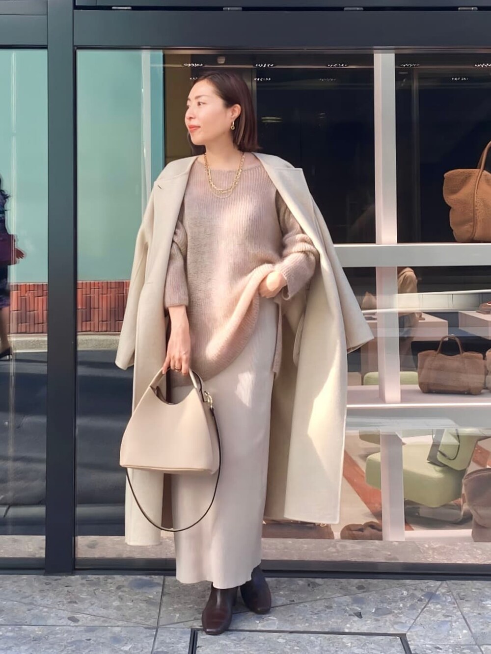 ベージュ系のスカート、ブラック系のブーツ、ベージュ系のニット/セーターを着用したレディースの秋コーディネートの2枚目の写真