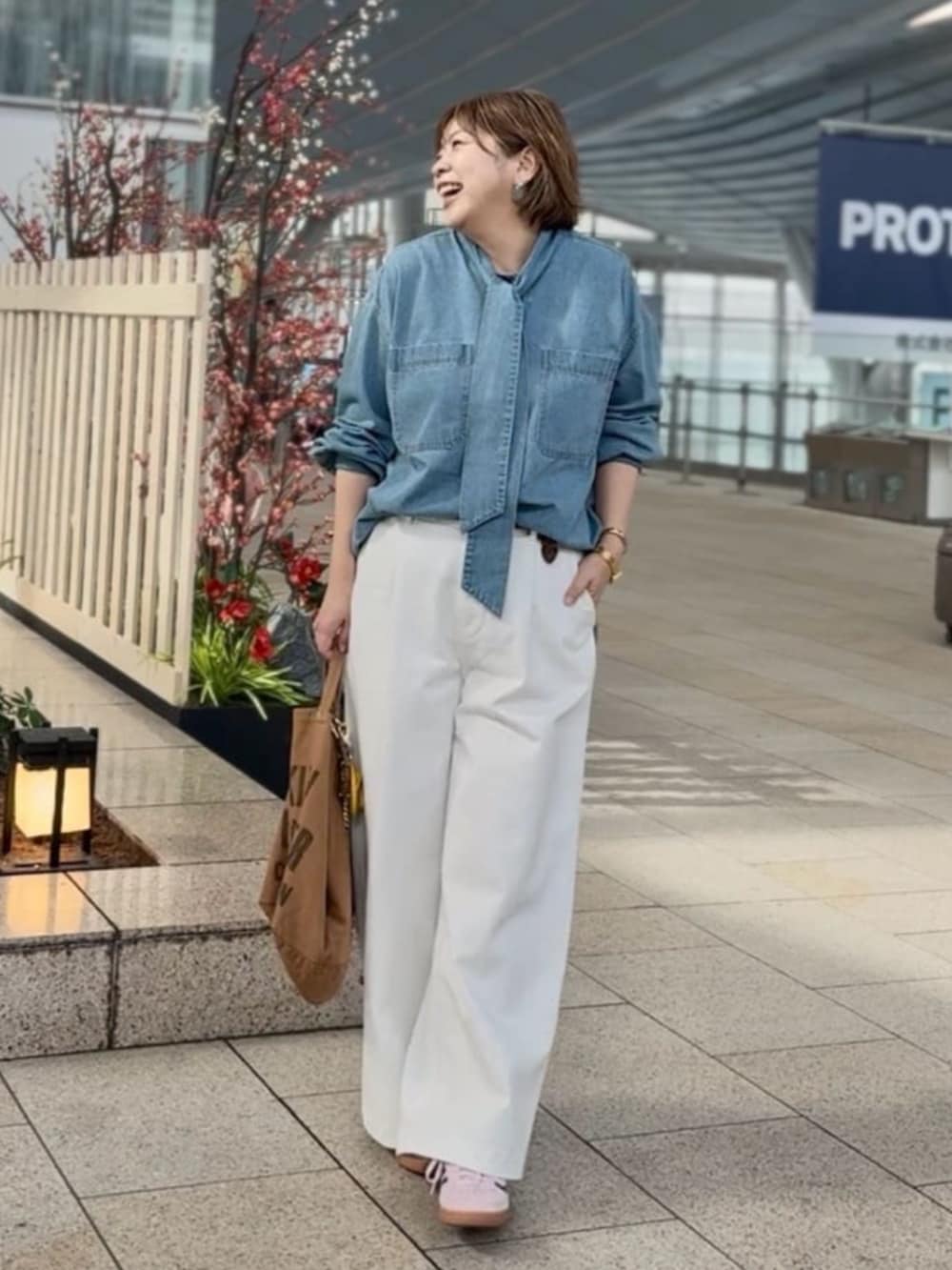 ホワイト系のデニムパンツ、ブルー系のシャツ/ブラウス、ブラウン系のベルトを着用したレディースの春コーディネートの2枚目の写真