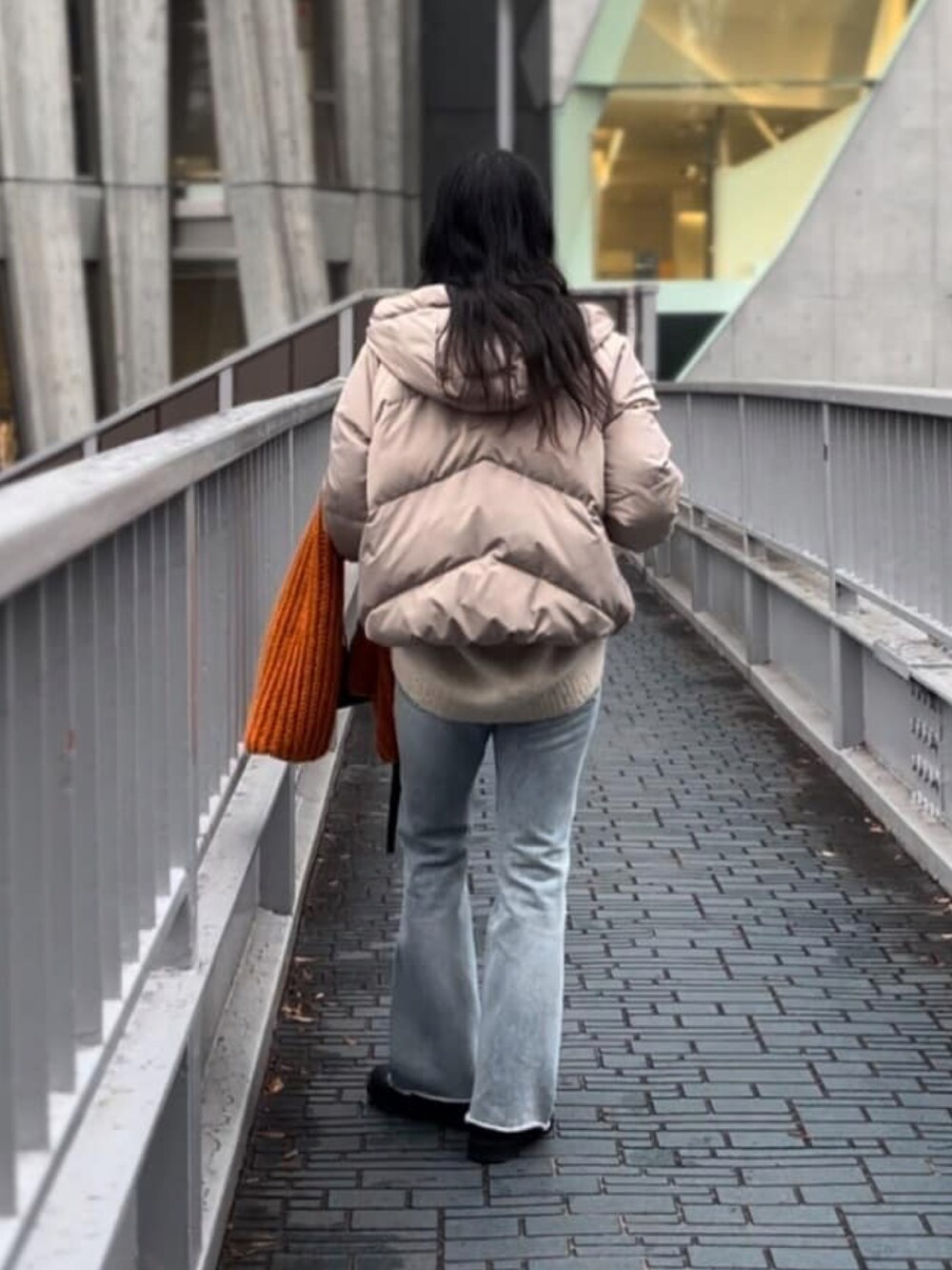 ブラック系のダウンジャケット/コート、ブルー系のデニムパンツ、ブラック系のブーツを着用したレディースの冬コーディネートの3枚目の写真