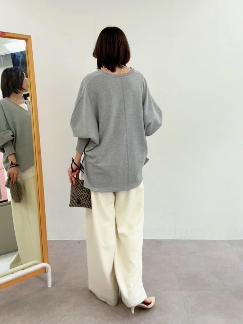 グレー系のスウェット、ホワイト系のスラックス、ホワイト系のキャミソールを着用したレディースの冬コーディネートの3枚目の写真