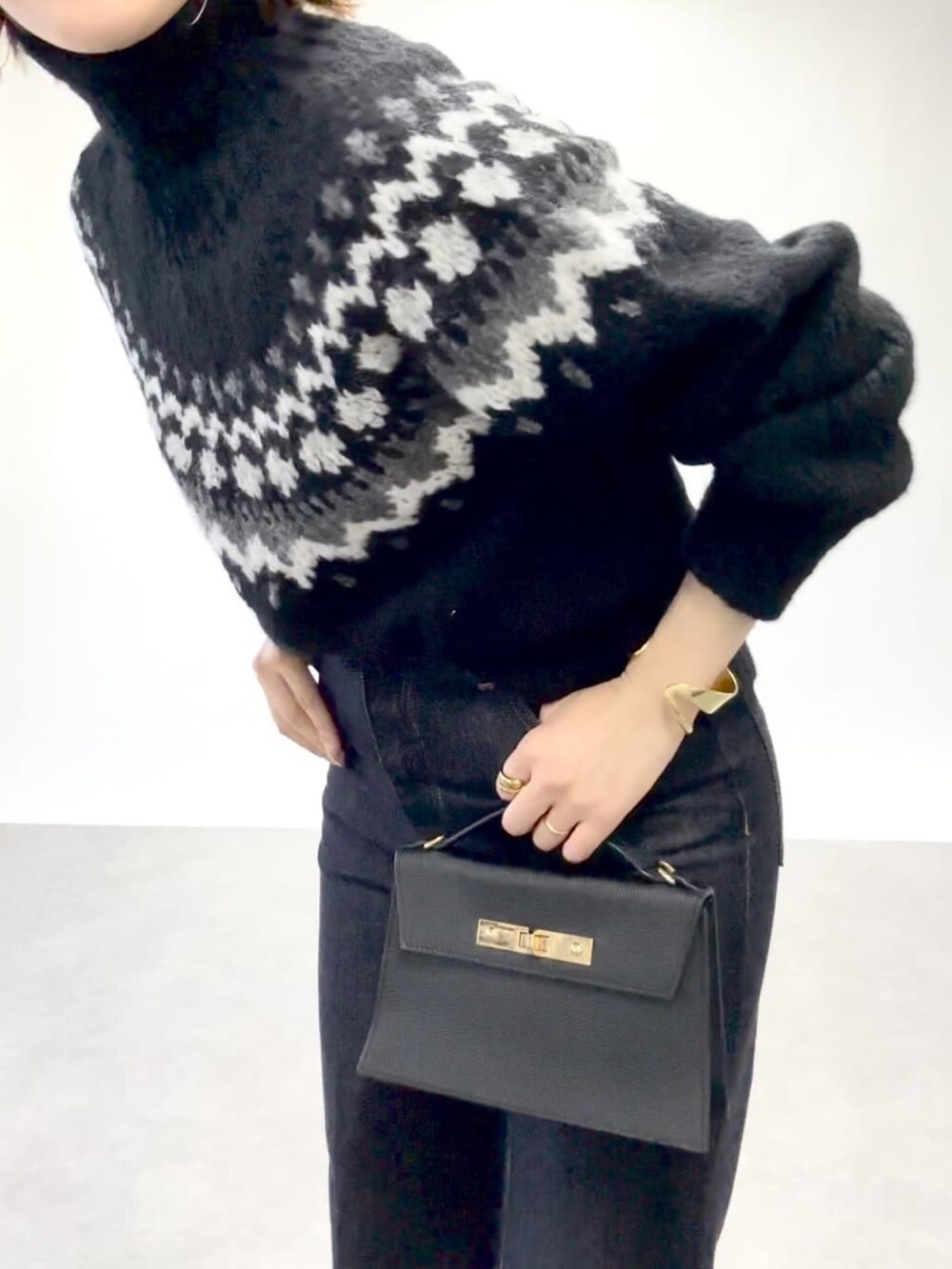 イエロー系のピーコート、ブルー系のデニムパンツ、ブラック系のニット/セーターを着用したレディースの冬コーディネートの3枚目の写真