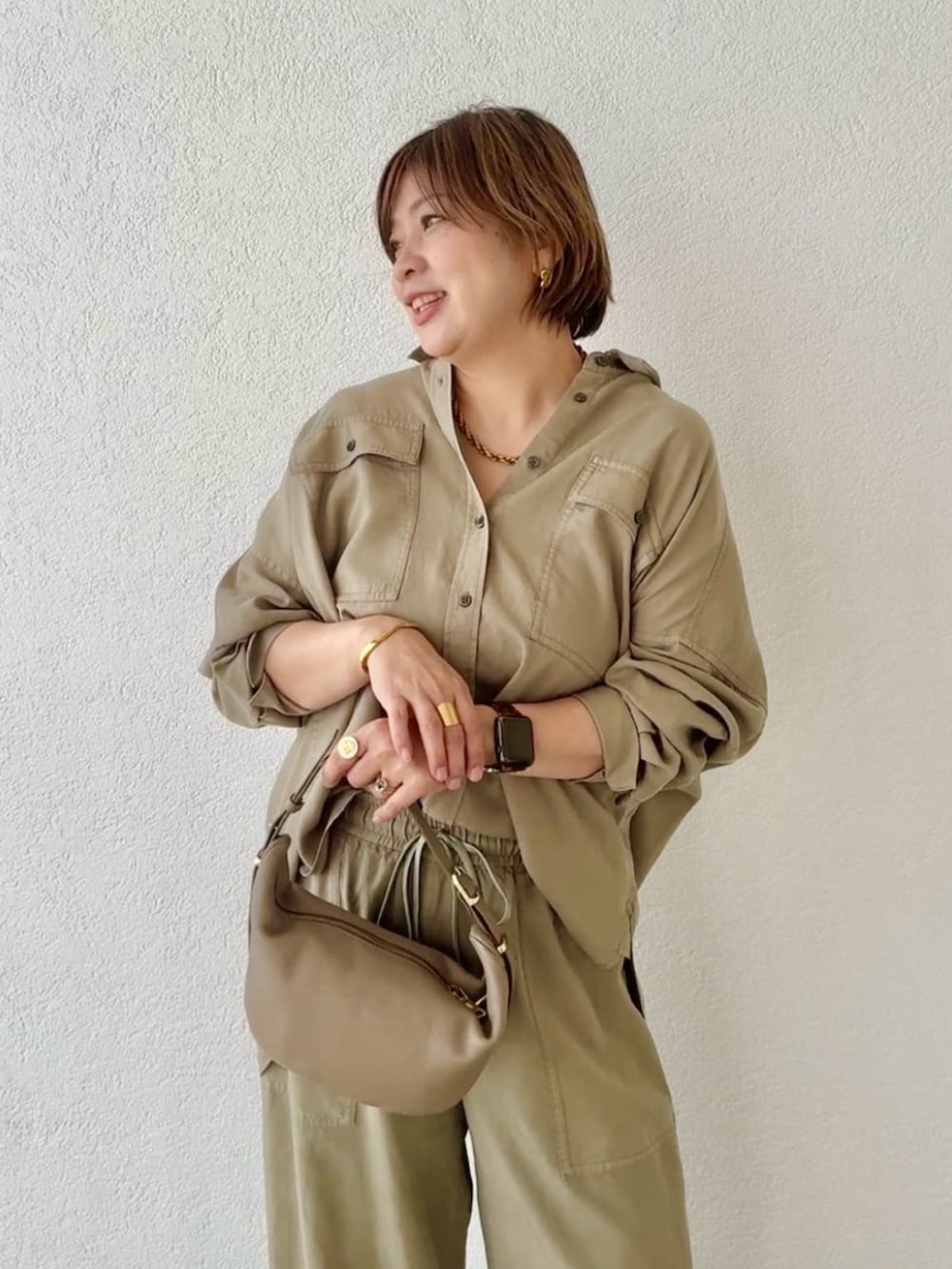 ベージュ系のその他シューズ、グリーン系のシャツ/ブラウス、ベージュ系のショルダーバッグを着用したレディースの春コーディネートの3枚目の写真