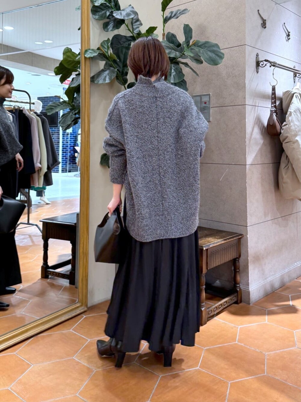 グレー系のニット/セーター、ブラック系のスカート、ブラック系のブーツを着用したレディースの冬コーディネートの3枚目の写真