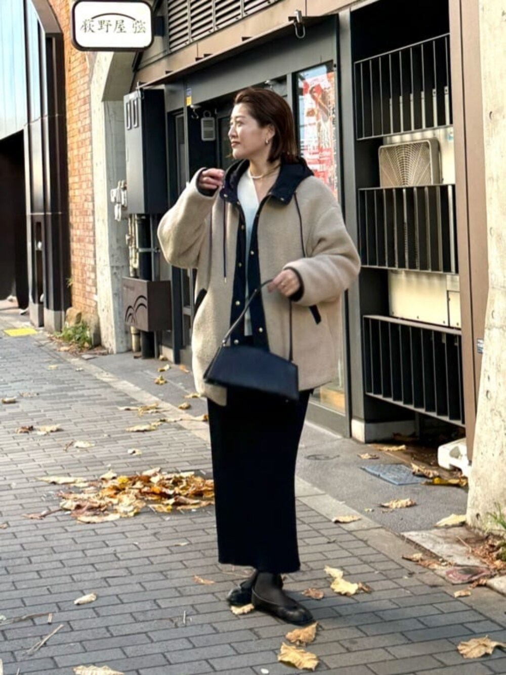 ブラック系のスカート、ブラック系のハンドバッグ、ブラック系のキャミソールを着用したレディースの冬コーディネートの2枚目の写真