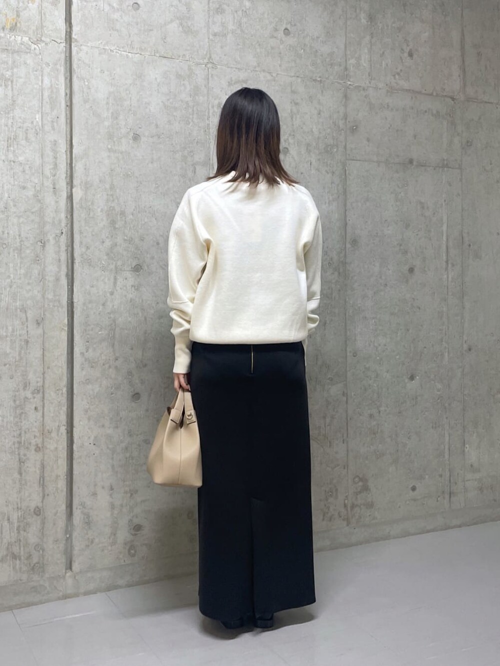 ホワイト系のニット/セーター、ベージュ系のトートバッグ、グリーン系のスカートを着用したレディースの冬コーディネートの3枚目の写真