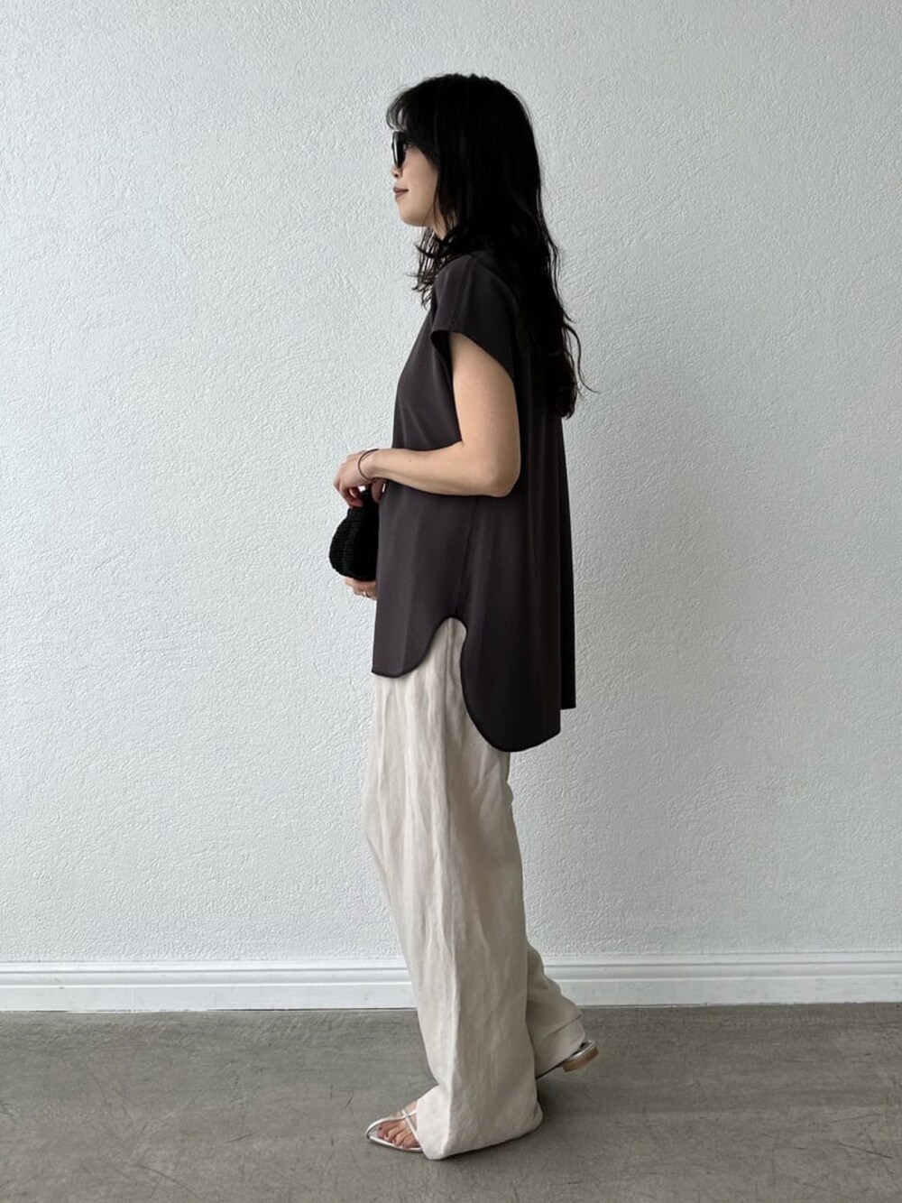 ベージュ系のパンツ、ゴールド系のショルダーバッグ、ブラック系のサンダルを着用したレディースの春コーディネートの2枚目の写真