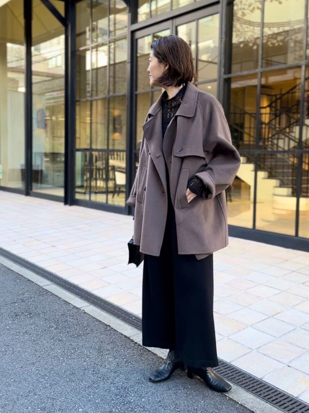 ブラウン系のその他アウター、ブラック系のサロペット/オーバーオール、ブラック系のブーツを着用したレディースの冬コーディネートの2枚目の写真