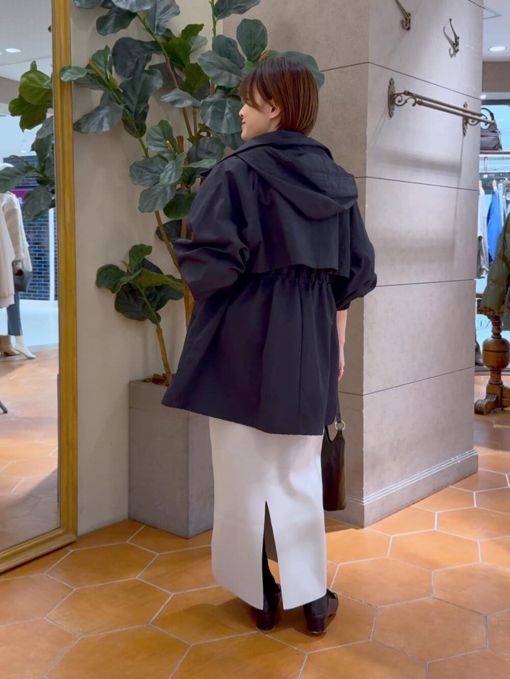 グレー系のニット/セーター、グレー系のスカート、ブラック系のマウンテンパーカーを着用したレディースの冬コーディネートの3枚目の写真