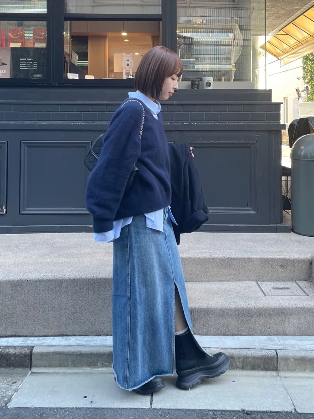 ブルー系のニット/セーター、ブルー系のデニムスカート、ブラック系のブーツを着用したレディースの冬コーディネートの2枚目の写真