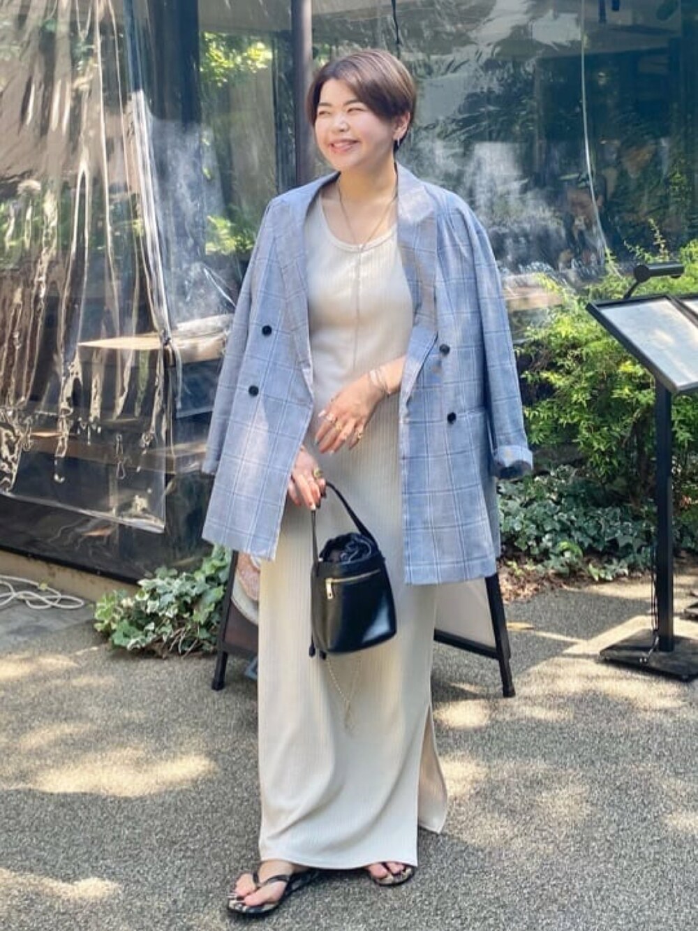 グレー系のテーラードジャケット、ブラック系のワンピース、ブラック系のハンドバッグを着用したレディースの夏コーディネートの2枚目の写真