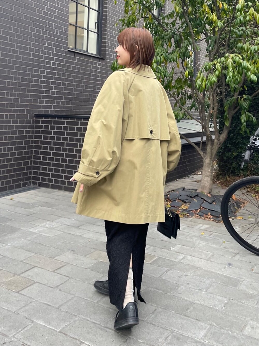 ベージュ系のトレンチコート、グレー系のスウェット、ブラック系のスカートを着用したレディースの冬コーディネートの4枚目の写真