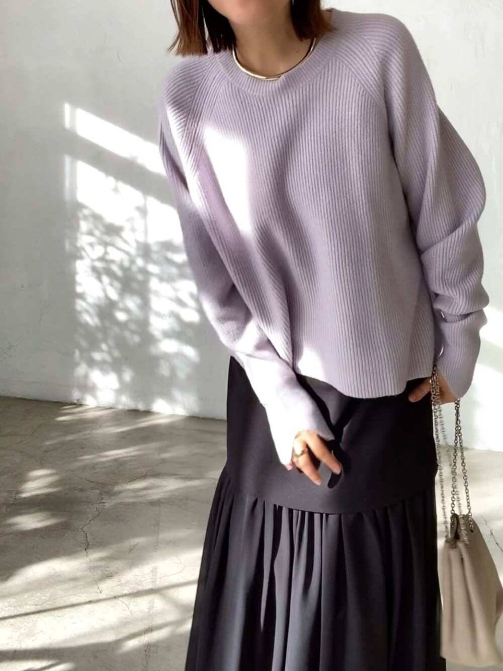 パープル系のニット/セーター、ベージュ系のショルダーバッグ、ブラック系のスカートを着用したレディースの冬コーディネートの3枚目の写真