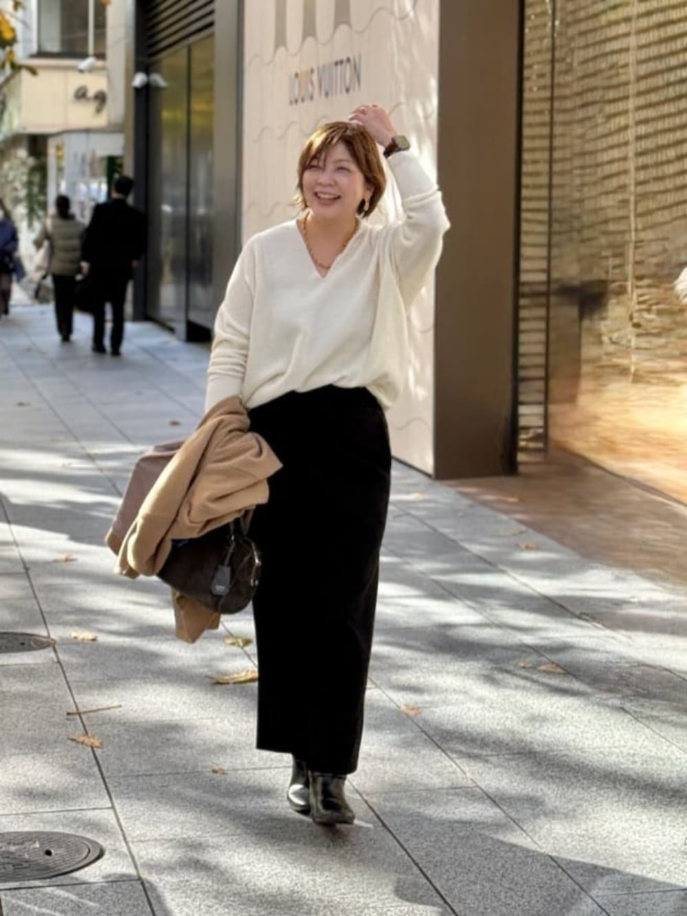 ホワイト系のニット/セーター、ブラック系のスカート、ゴールド系のネックレスを着用したレディースの冬コーディネートの4枚目の写真