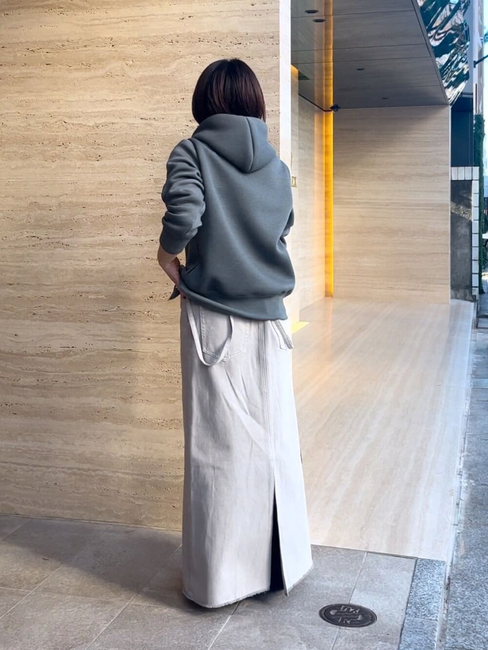 グレー系のパーカー、グレー系のデニムスカート、ブラック系のショルダーバッグを着用したレディースの冬コーディネートの3枚目の写真