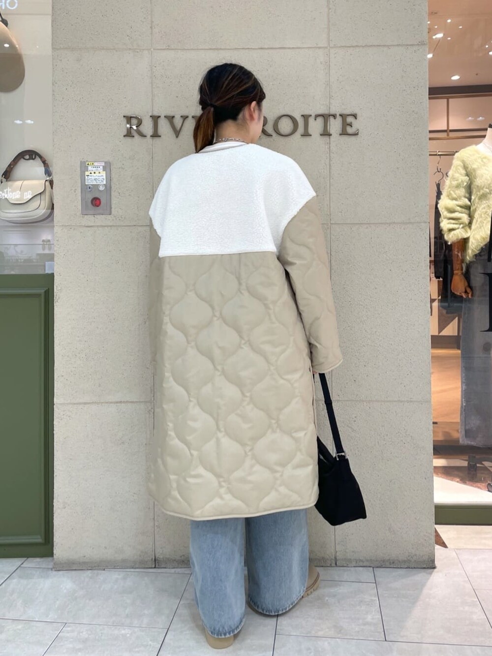 ベージュ系のダウンジャケット/コート、ブルー系のデニムパンツ、ブラック系のショルダーバッグを着用したレディースの秋コーディネートの3枚目の写真