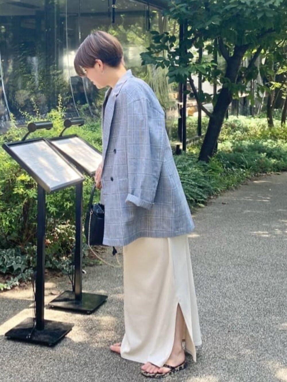 グレー系のテーラードジャケット、ブラック系のワンピース、ブラック系のハンドバッグを着用したレディースの夏コーディネートの3枚目の写真