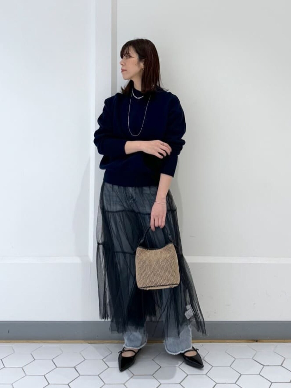 ブルー系のニット/セーター、ブラック系のスカート、ブラック系のハンドバッグを着用したレディースの春コーディネートの2枚目の写真