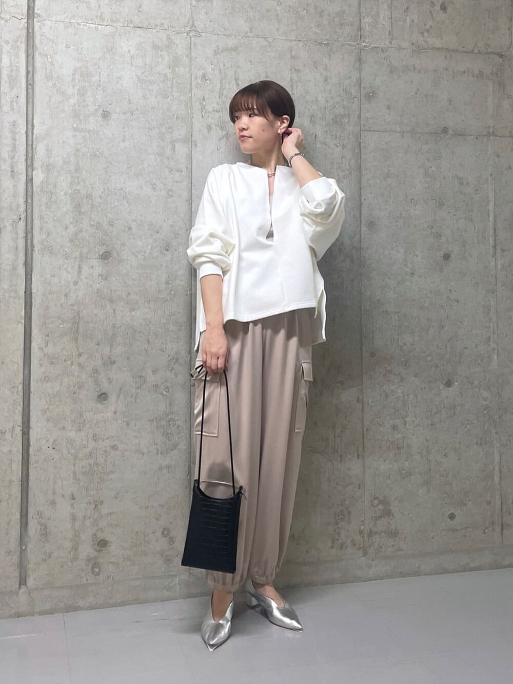 ホワイト系のスウェット、ベージュ系のカーゴパンツ、シルバー系のパンプスを着用したレディースの春コーディネートの2枚目の写真