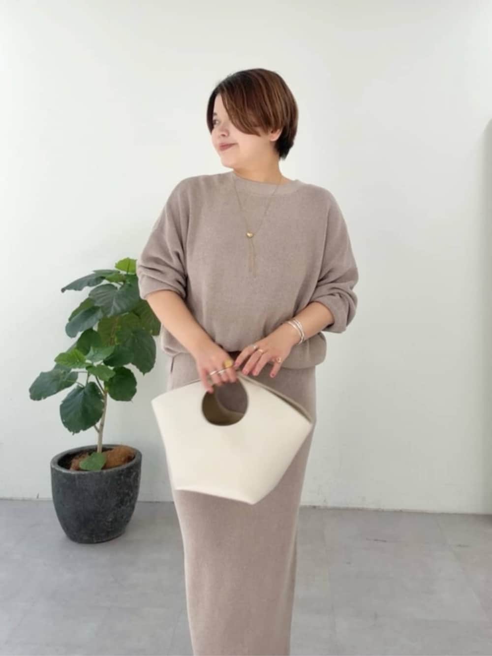 ホワイト系のハンドバッグ、ホワイト系のパーカー、ブラウン系のニット/セーターを着用したレディースの冬コーディネートの7枚目の写真