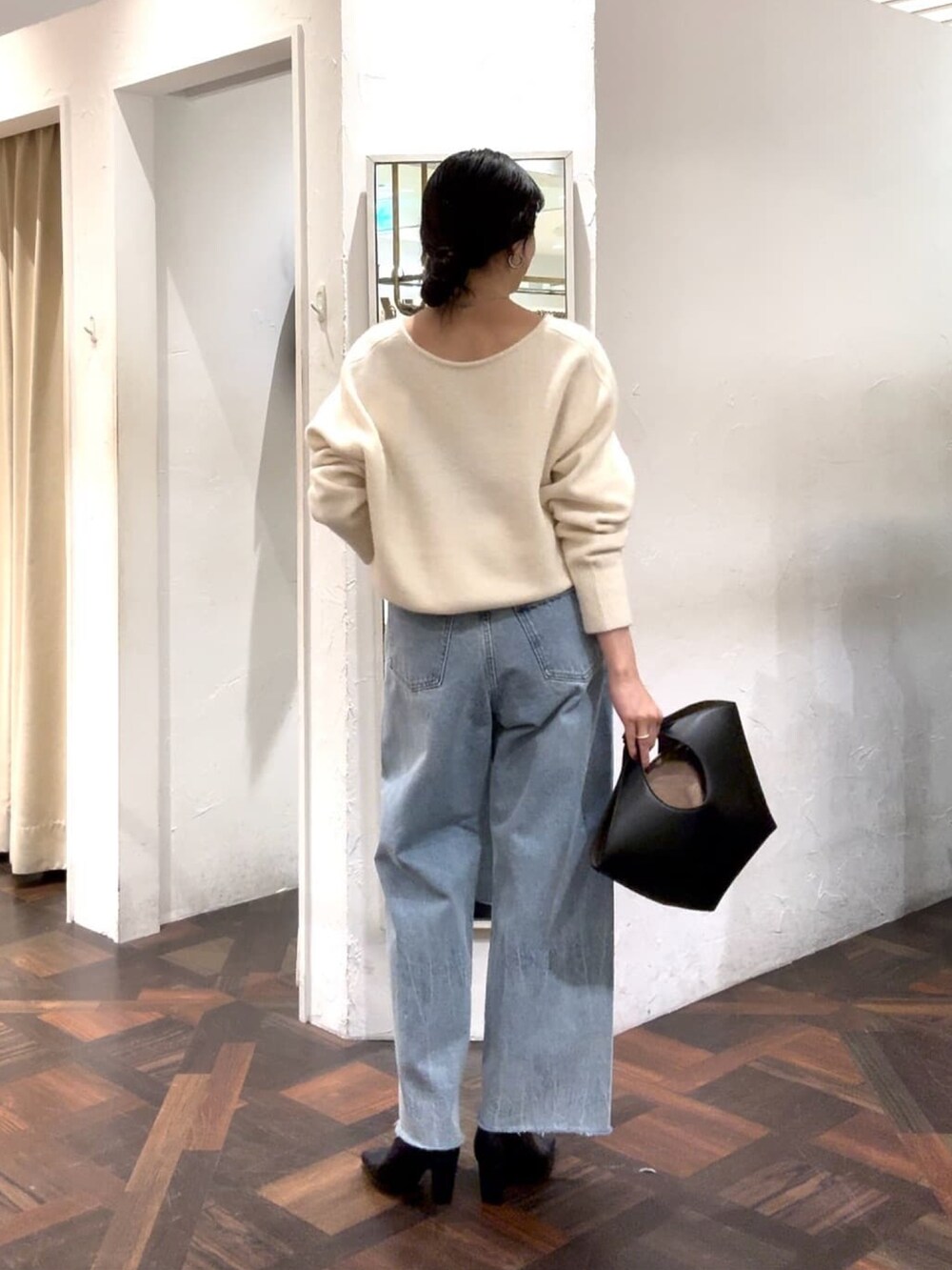 ホワイト系のニット/セーター、ブラック系のハンドバッグ、ブルー系のデニムパンツを着用したレディースの冬コーディネートの5枚目の写真