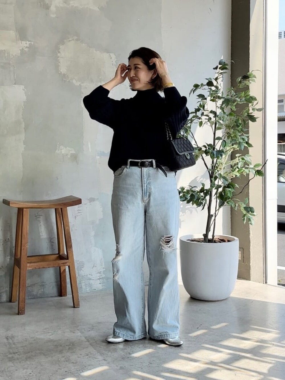 ブルー系のニット/セーター、ブラック系のショルダーバッグ、ブルー系のデニムパンツを着用したレディースの冬コーディネートの2枚目の写真