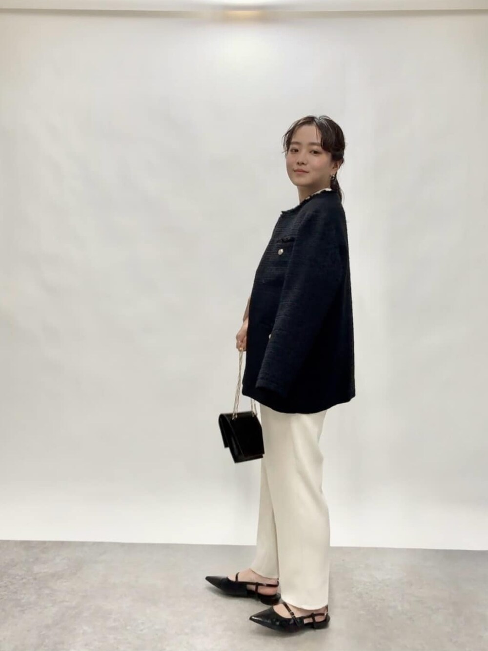 ブルー系のノーカラージャケット、ブラック系のショルダーバッグ、ホワイト系のその他パンツを着用したレディースの冬コーディネートの2枚目の写真