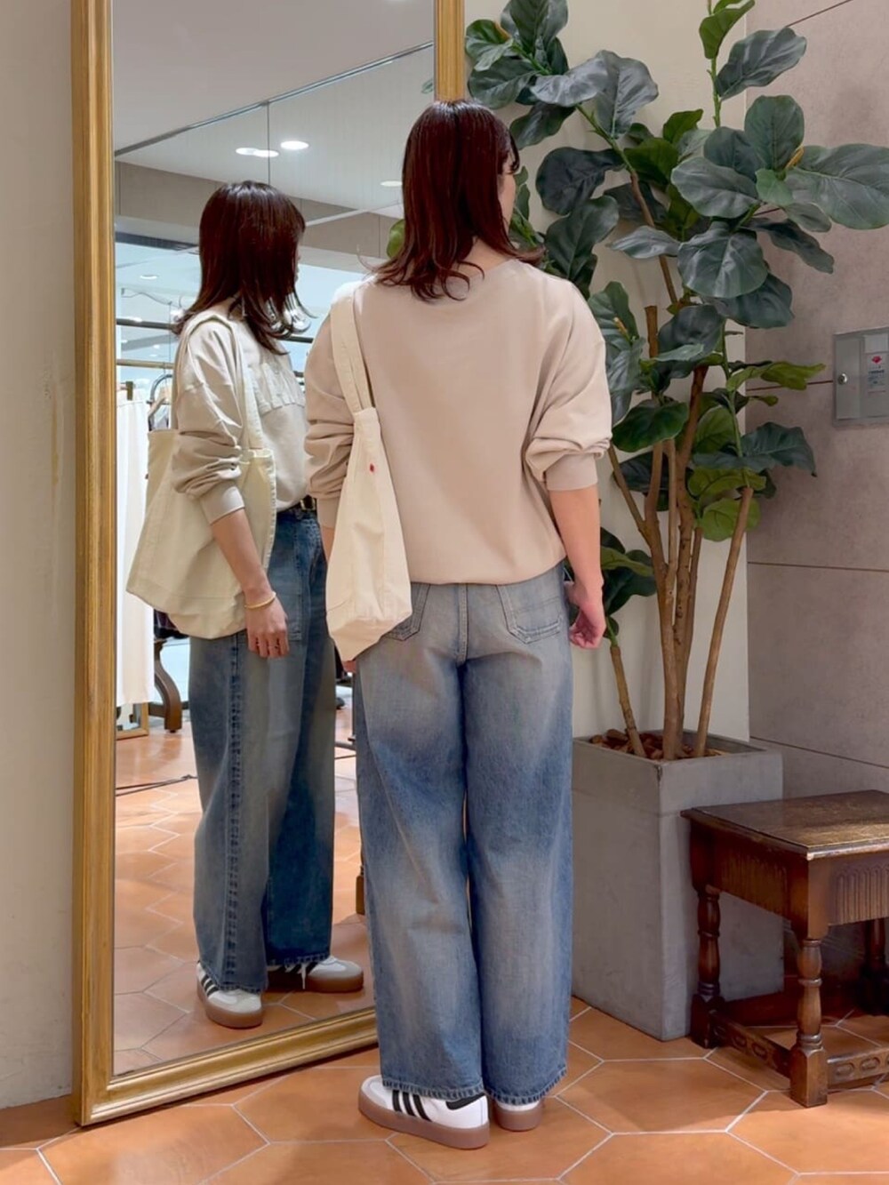 ベージュ系のスウェット、ホワイト系のトートバッグ、ブルー系のデニムパンツを着用したレディースの冬コーディネートの4枚目の写真