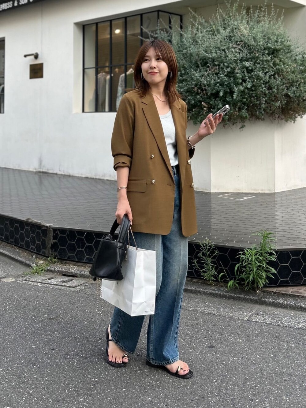 シルバー系のタンクトップ、ブラウン系のテーラードジャケット、ブルー系のデニムパンツを着用したレディースの夏コーディネートの2枚目の写真