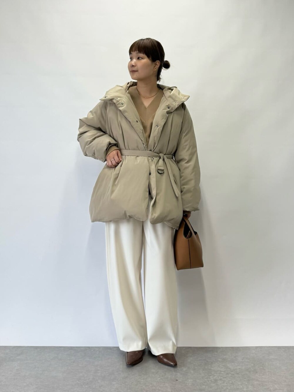 ベージュ系のダウンジャケット/コート、イエロー系のハンドバッグ、ホワイト系のその他パンツを着用したレディースの冬コーディネートの2枚目の写真