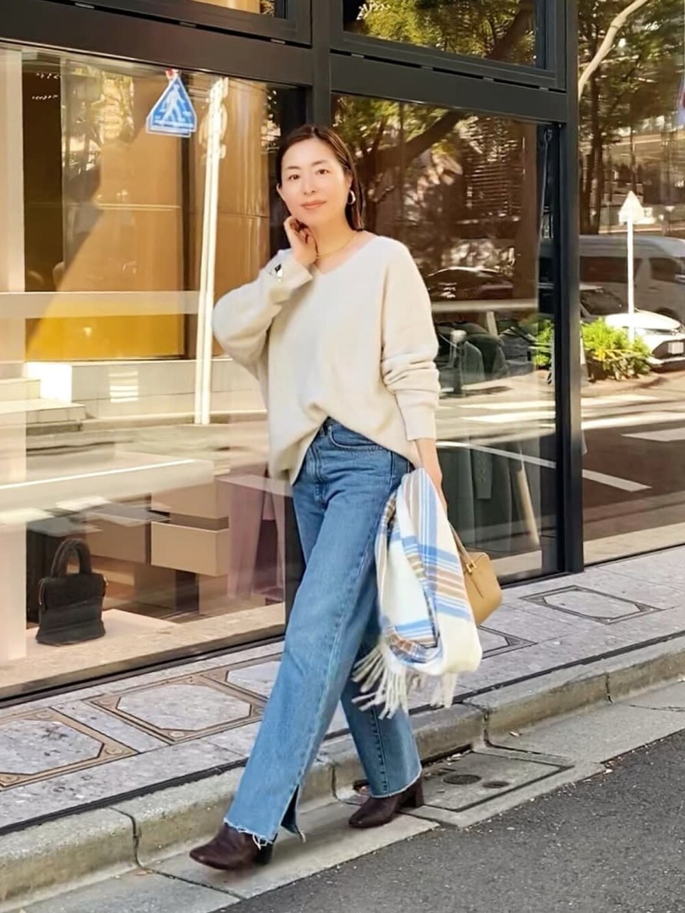 ブルー系のデニムパンツ、ホワイト系のダウンジャケット/コート、ベージュ系のニット/セーターを着用したレディースの秋コーディネートの3枚目の写真