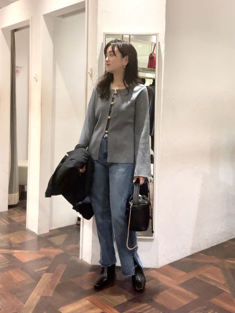 グレー系のカーディガン/ボレロ、ブルー系のデニムパンツ、ブラック系のハンドバッグを着用したレディースの秋コーディネートの2枚目の写真
