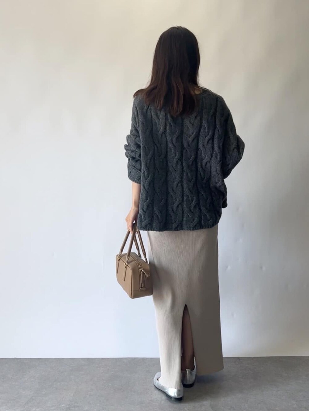 ベージュ系のスカート、グレー系のニット/セーター、イエロー系のボストンバッグを着用したレディースの秋コーディネートの4枚目の写真