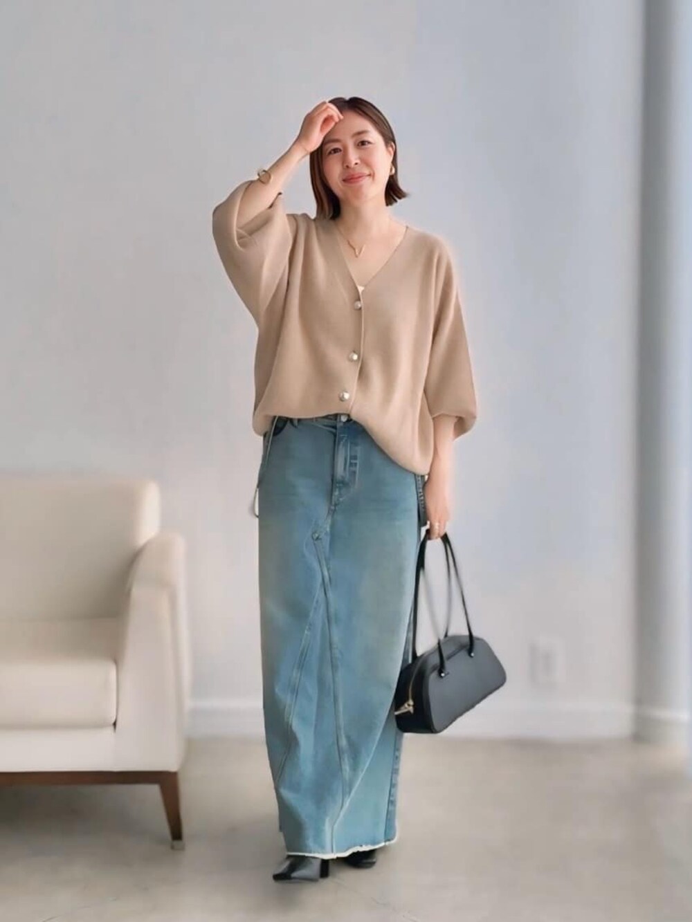 ベージュ系のカーディガン/ボレロ、ブルー系のデニムスカート、ブラック系のショルダーバッグを着用したレディースの秋コーディネートの4枚目の写真