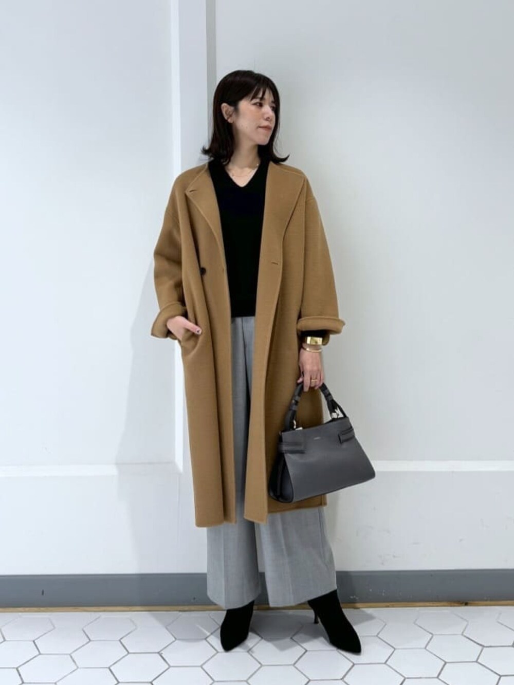 ブラック系のニット/セーター、グレー系のその他パンツ、ブラック系のブーツを着用したレディースの冬コーディネートの2枚目の写真