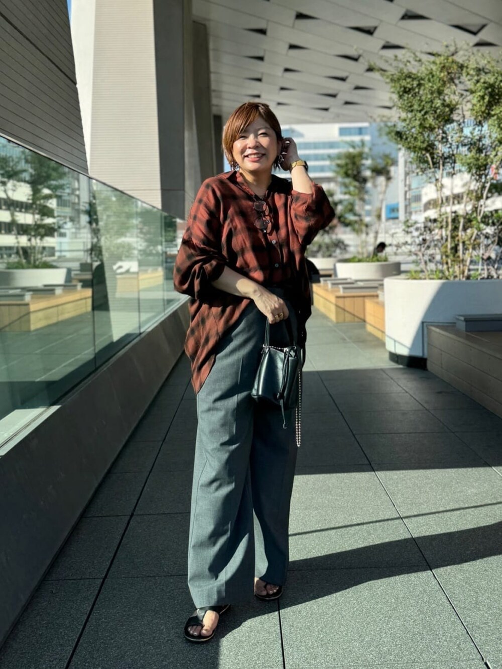 ブラック系のハンドバッグ、グレー系のその他パンツ、ブラウン系のシャツ/ブラウスを着用したレディースの夏コーディネートの2枚目の写真