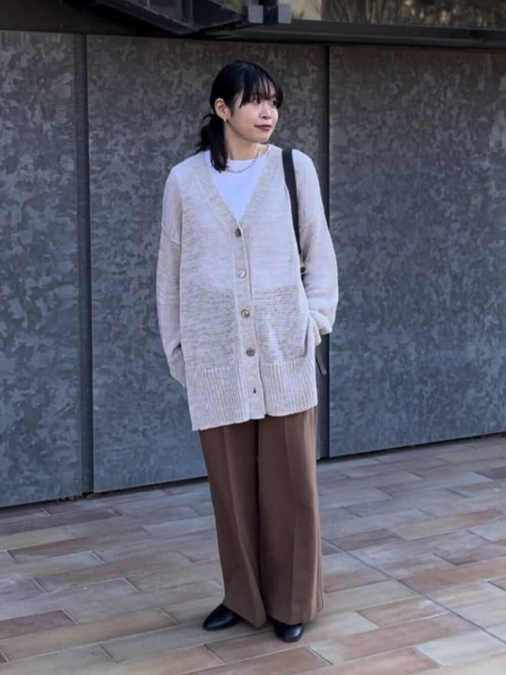 ベージュ系のステンカラーコート、ホワイト系のTシャツ/カットソー、ブラウン系のカーディガン/ボレロを着用したレディースの春コーディネートの2枚目の写真