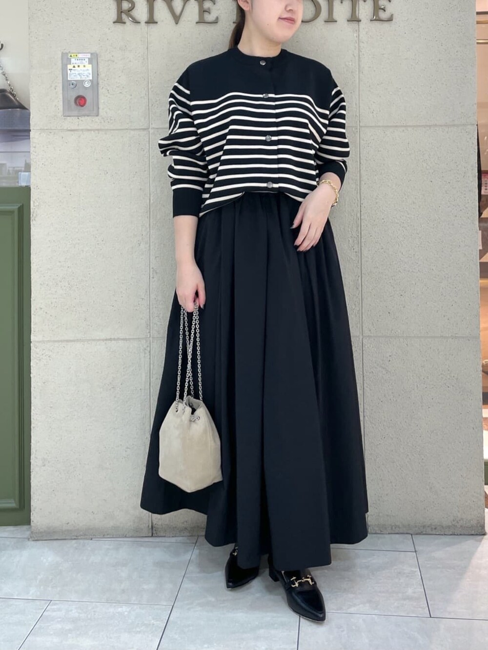 ブラック系のニット/セーター、ブラック系のスカート、ブラック系のローファーを着用したレディースの秋コーディネートの2枚目の写真