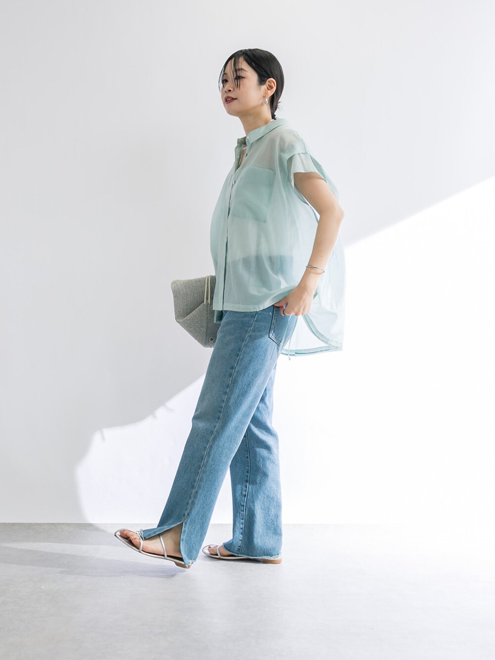 ブルー系のデニムパンツ、シルバー系のサンダル、グリーン系のシャツ/ブラウスを着用したレディースの春コーディネートの2枚目の写真