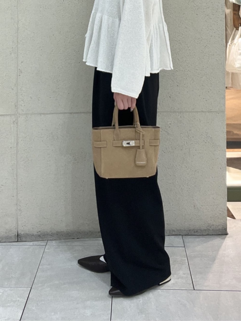 ベージュ系のトートバッグ、ブラウン系のその他シューズ、ホワイト系のニット/セーターを着用したレディースの春コーディネートの8枚目の写真