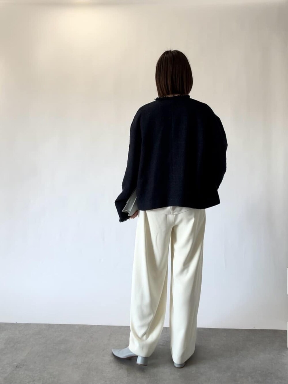 ブルー系のノーカラージャケット、ホワイト系のスラックス、ブルー系のパンプスを着用したレディースの冬コーディネートの3枚目の写真