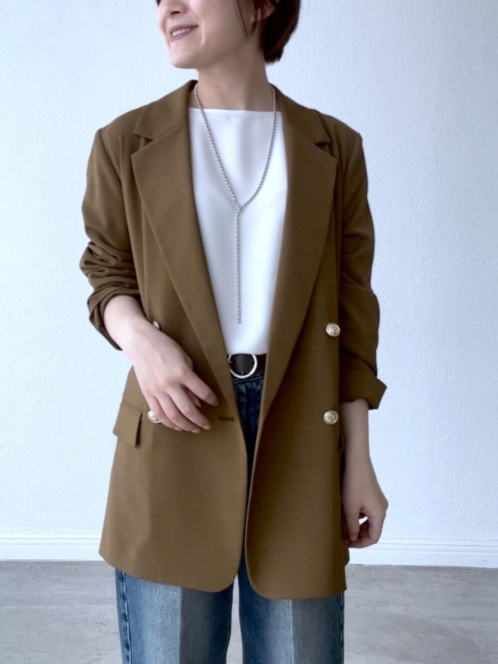 ホワイト系のシャツ/ブラウス、ブラウン系のテーラードジャケット、ブルー系のデニムパンツを着用したレディースの夏コーディネートの3枚目の写真