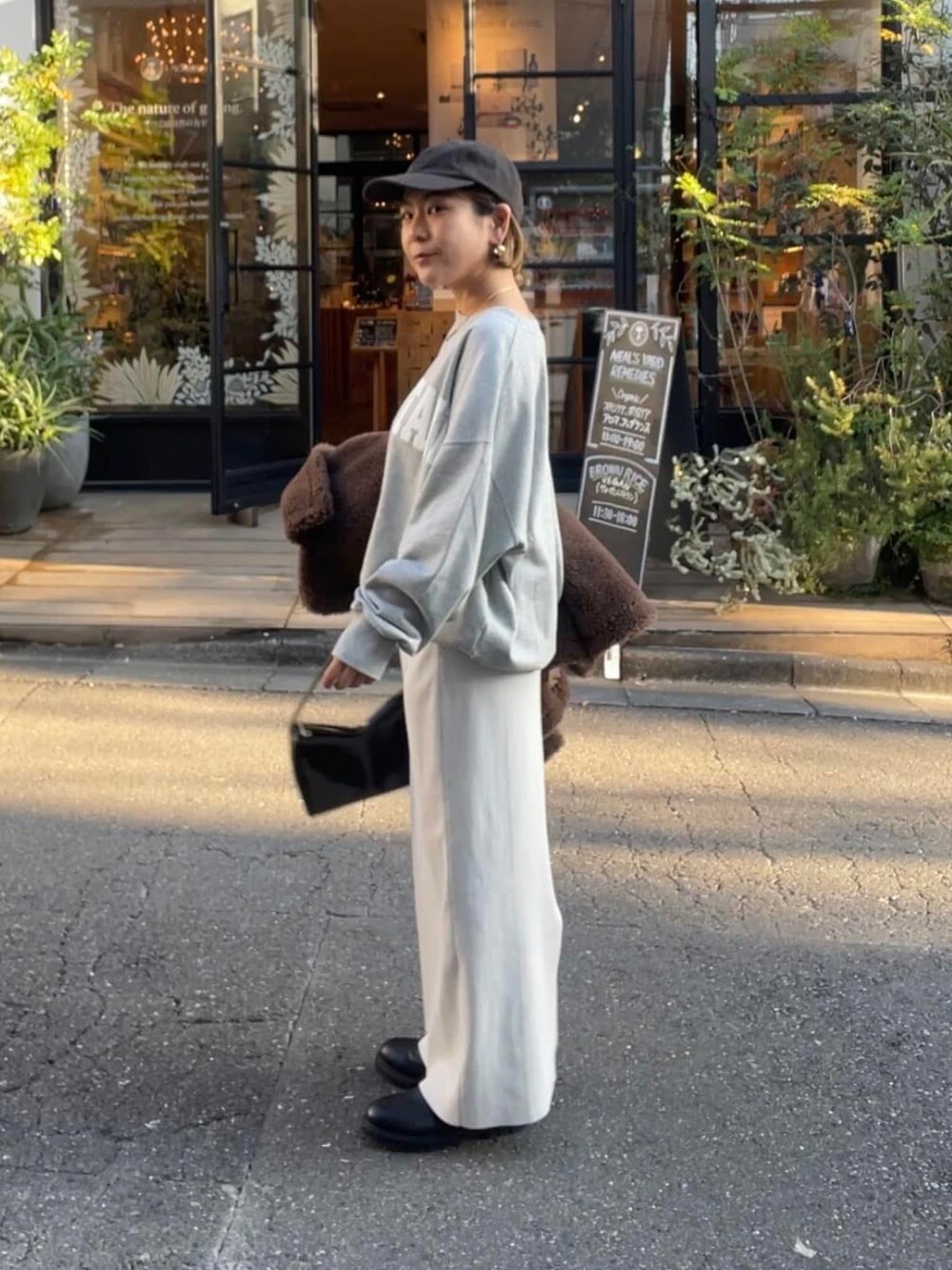 ブラウン系のスカート、ブラック系のショルダーバッグ、グレー系のスウェットを着用したレディースの冬コーディネートの2枚目の写真