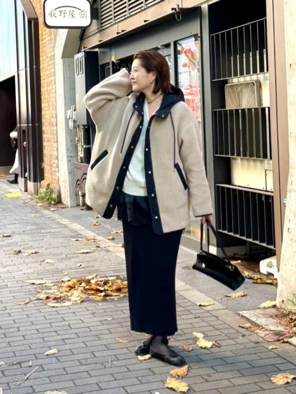 ブラック系のスカート、ブラック系のハンドバッグ、ブラック系のキャミソールを着用したレディースの冬コーディネートの4枚目の写真