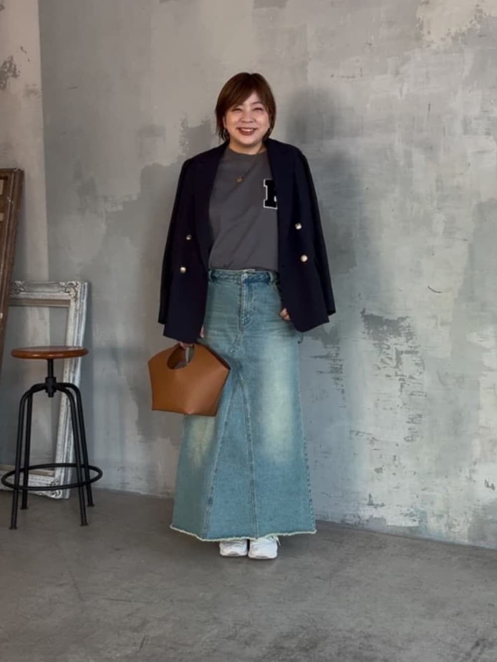 グレー系のTシャツ/カットソー、ブルー系のデニムスカート、イエロー系のハンドバッグを着用したレディースの冬コーディネートの3枚目の写真